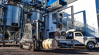 A forklift truck and a pick-up truck transport wooden barrels of spirits